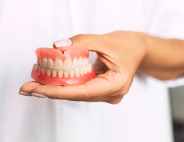 Dentist holding full dentures in Aspen Hill