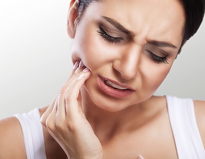 Woman in need of tooth extraction holding jaw in pain