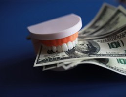 fake teeth holding onto money in Aspen Hill