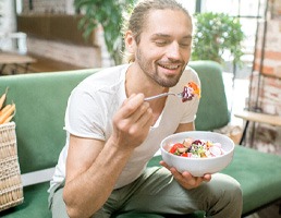 Man smiling while eating healthy lunch at home