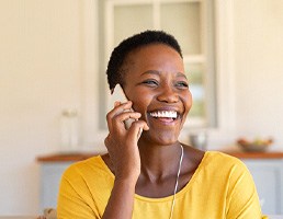 Woman in yellow shirt smiling while talking on phone