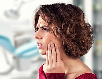 Woman in need of emergency dentistry holding jaw