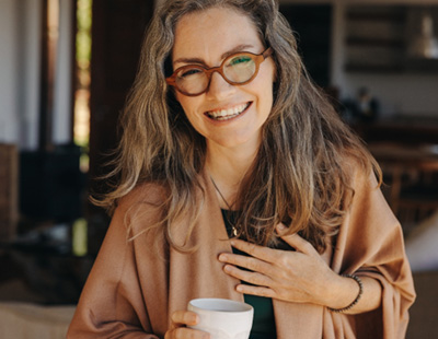 Senior woman smiling with glasses and coffee cup