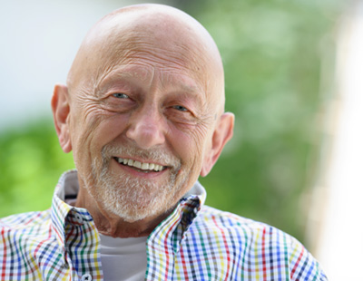 Senior man in colorful shirt smiling outside