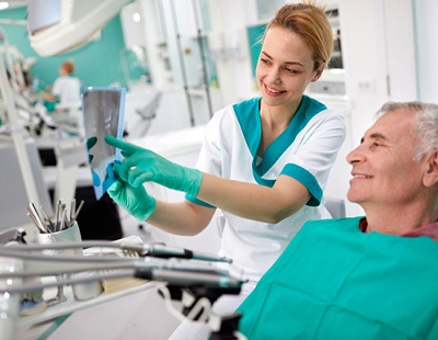 A dentist shows an older, male patient his dental X-Rays and where the necessary dental crown will be placed