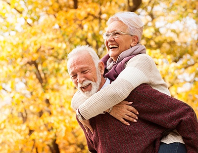 A happy, older couple outside and smiling after receiving dentures in Aspen Hill