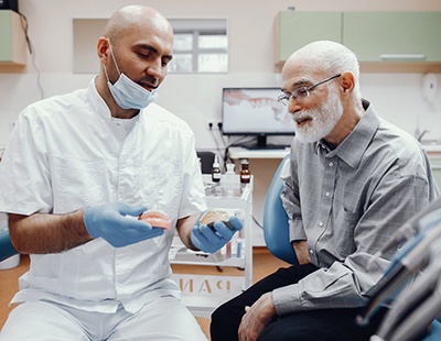 An older man talking to a dentist about dentures
