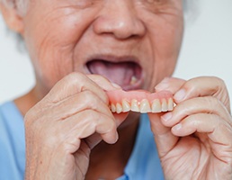 a person putting on their new dentures in Aspen Hill