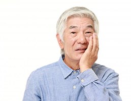 man holding his face and worrying about the cost of dental emergencies