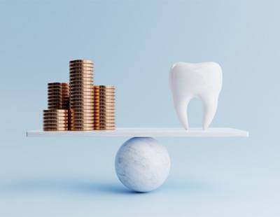 coins and a tooth balancing on a scale 