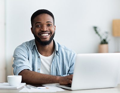 a smiling person working on their laptop after Invisalign treatment