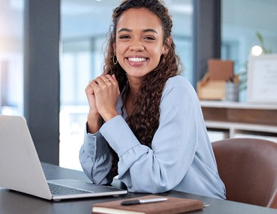 Woman smiling while working on laptop in office