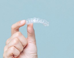 Patient holding up Invisalign clear aligner
