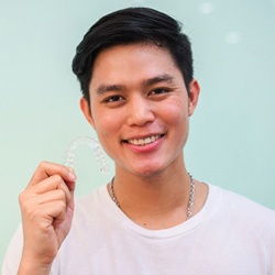 Man in white t shirt and necklace holding Invisalign