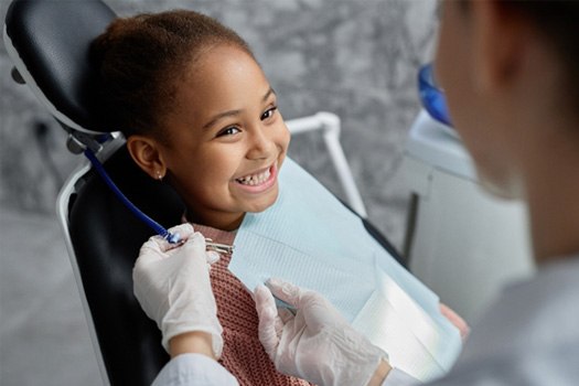 Girl in dental chair grinning at dentist 