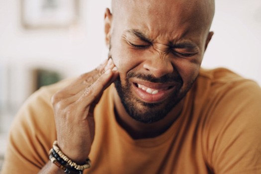 Man pressing hand to jaw in pain