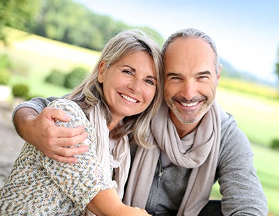 Older man and woman smiling after dental implant tooth replacement