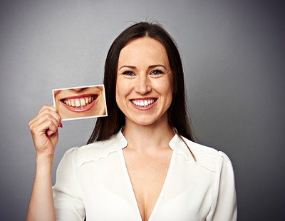 Woman holds before and after photos of teeth whitening in Aspen Hill