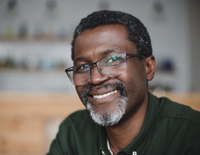 An older gentleman wearing glasses and smiling after receiving tooth-colored fillings in Aspen Hill