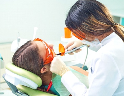 A dentist uses a special curing light to harden the composite resin into place