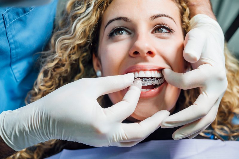A dentist placing Invisalign aligners on a patient’s teeth