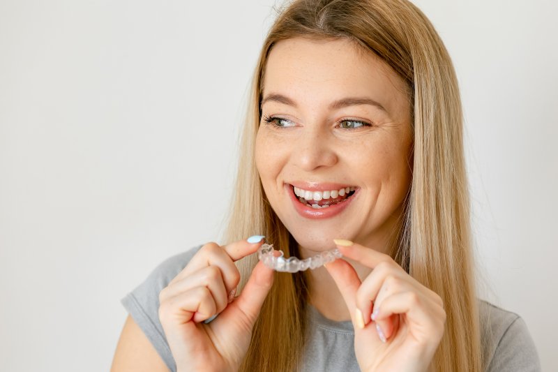 A cheerful woman holding an Invisalign aligner