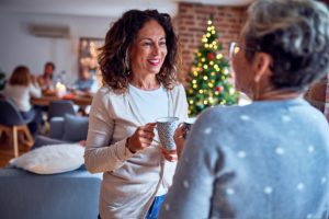 Two women chatting over coffee with a Christmas tree in the background