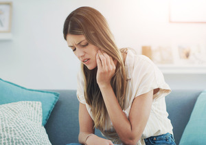 Woman with jaw pain sitting on couch